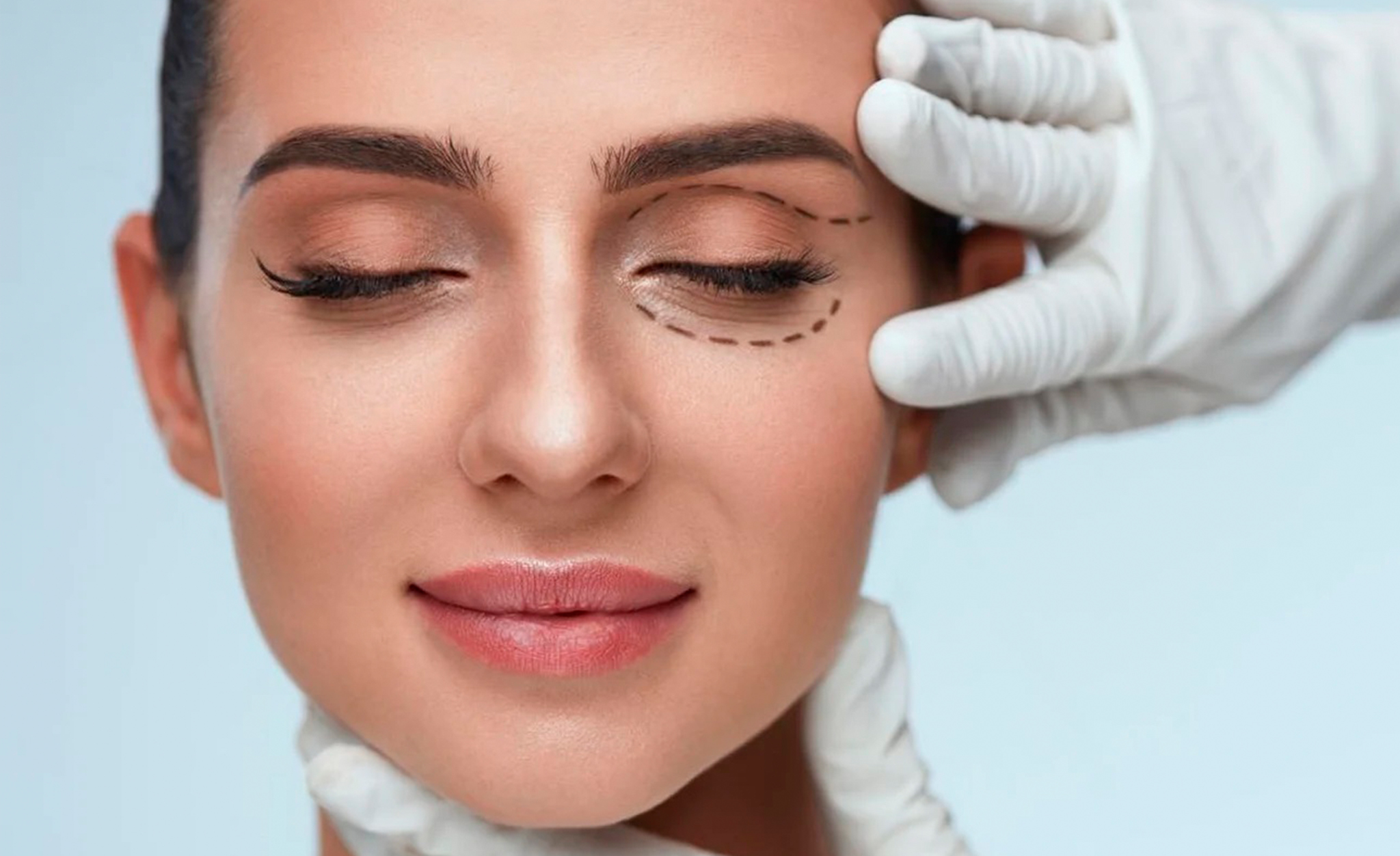 Plastic surgeon applying marking on male face against light background